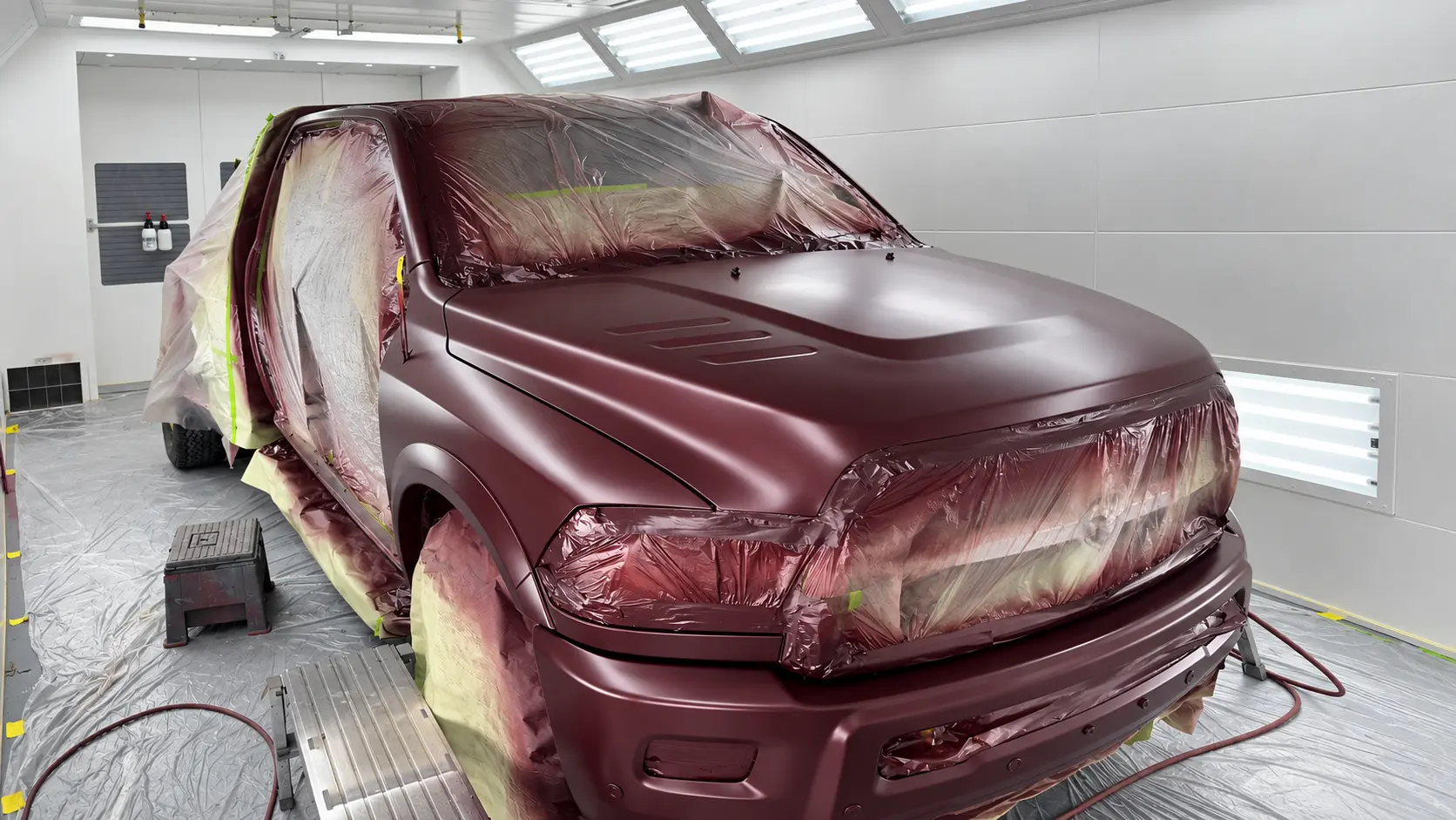 Masked maroon truck being refinished inside the Rayco paint booth