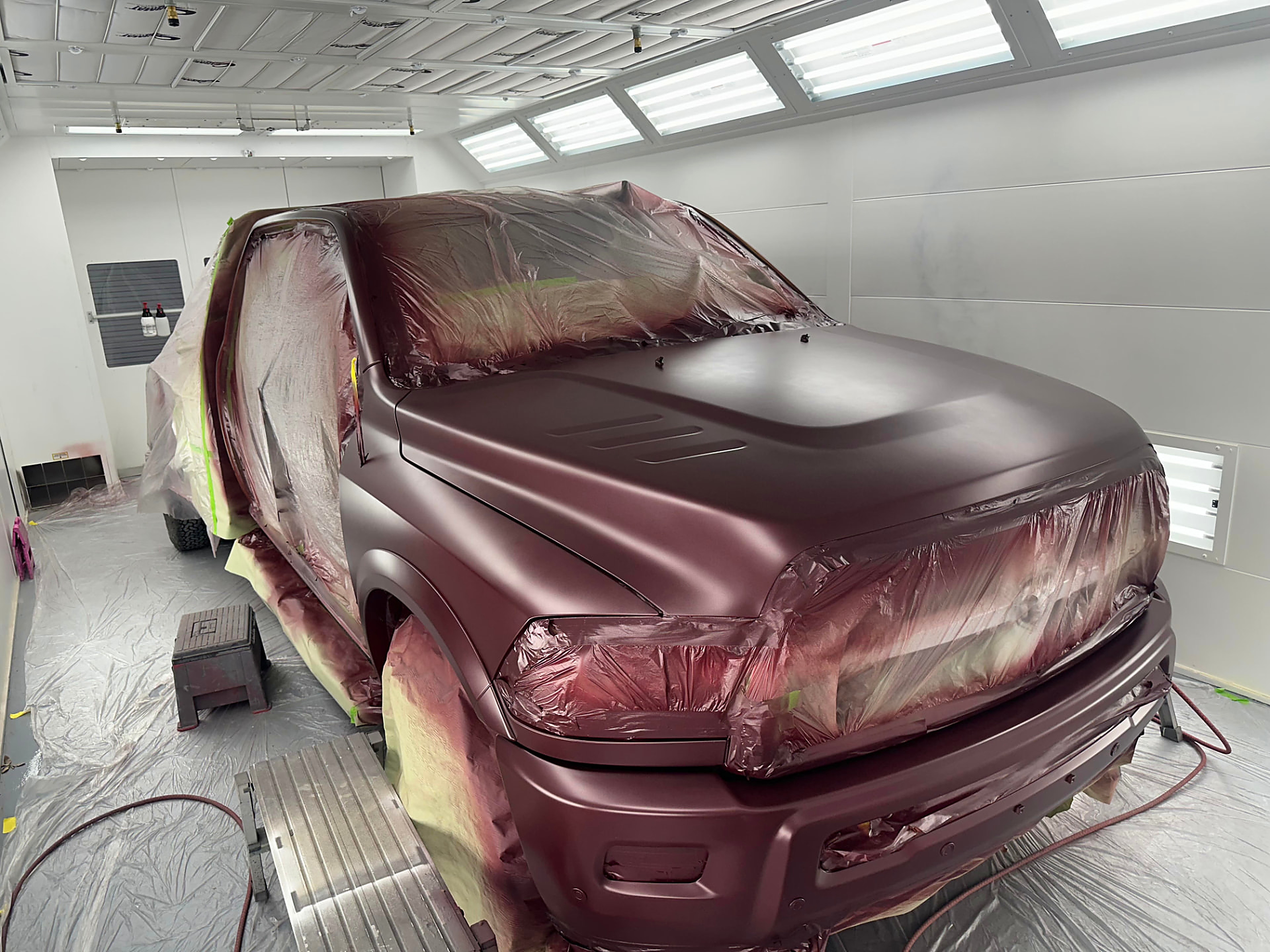 Ram truck in fresh maroon paint inside the Rayco downdraft paint booth