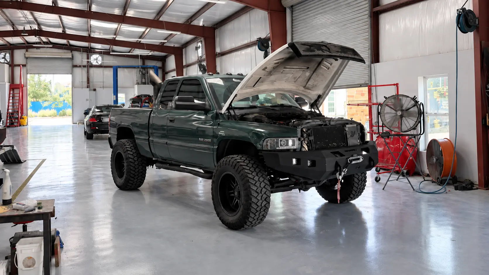 Green Ram truck with its hood open inside the Rayco shop